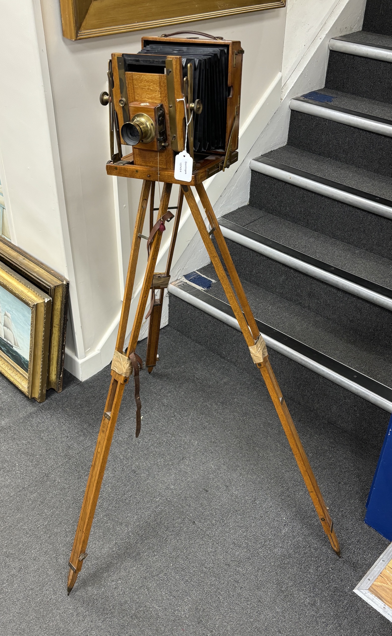 An early 20th century brass and mahogany ‘Sanderson’ half plate bellows camera by G.H.&S., London, with a lens and a shutter action by Thornton Pickard, on an oak tripod